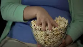 Close-up Of A Person Grabbing Popcorn From A Glass Bowl